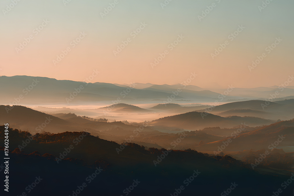 Fototapeta premium Serene Mountain Silhouette at Sunset: The majestic mountains are silhouetted against a pastel sky, as the sun dips below the horizon, casting a soft, golden glow over the landscape. 