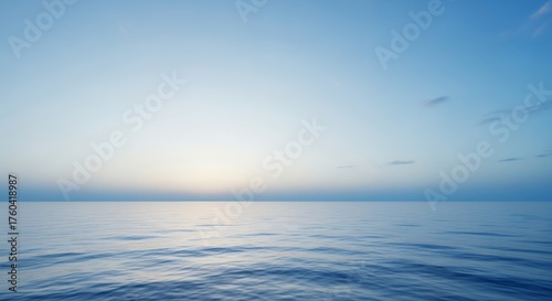 Calm ocean reflecting early morning sky with pale sunlight on the horizon and gentle ripples. Concept for peaceful meditation, travel destinations and nature backgrounds