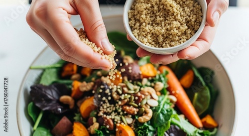 Close-up shot of two hands sprinkling sesame seeds over a vibrant mixed salad with vegetables in a white bowl on a clean white surface.