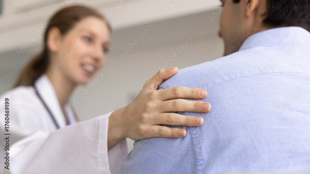Fototapeta premium Compassionate female doctor gently touches male patient shoulder