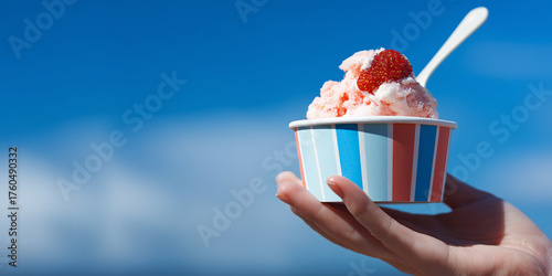 Ice cream in woman hand by the sea. Delicious ice cream topped with fresh strawberry. Perfect for summer branding