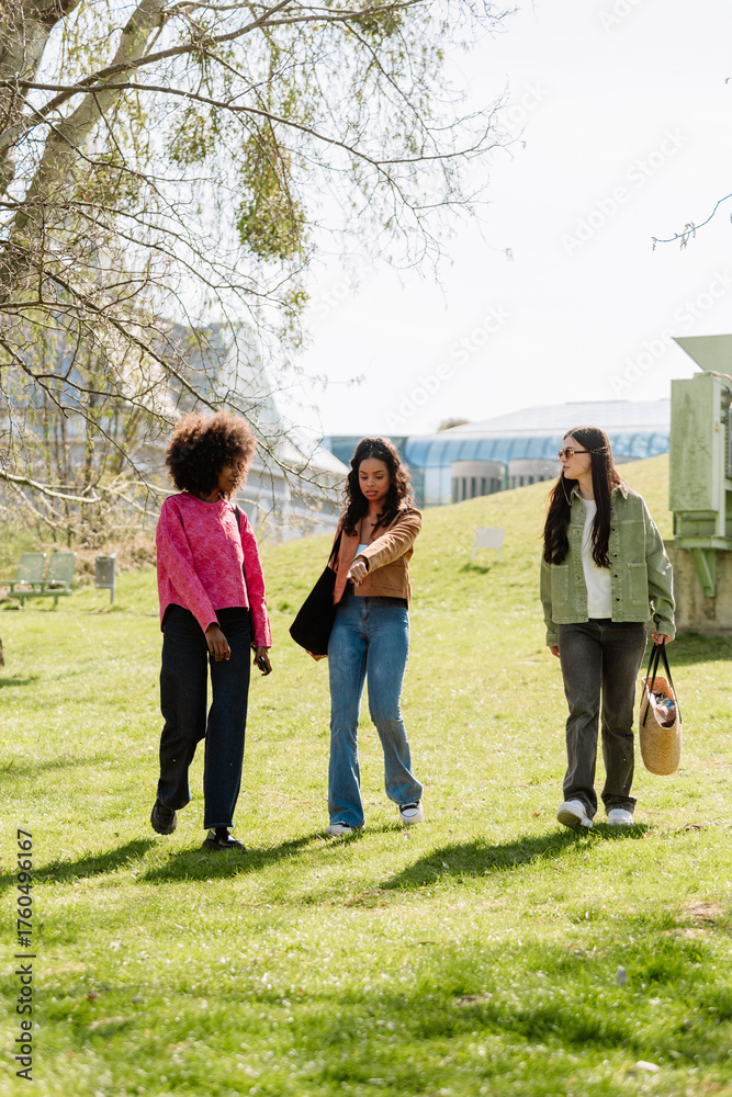 Obraz premium A group of three female friends walking and talking while one of them holds her hand in front of her