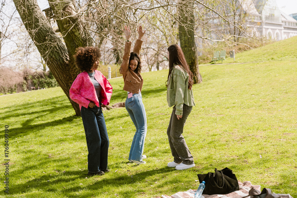 Obraz premium A woman has her arms raised and smiles while dancing with two female friends