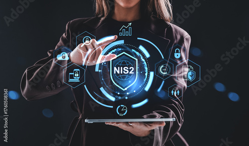 Businesswoman interacts with NIS2 cybersecurity hologram interface concept over tablet on dark background in modern digital technology scene..