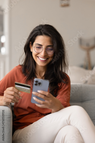 Cheerful Latin web store customer woman paying by credit card
