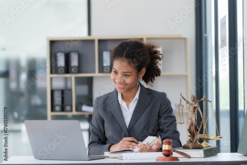An American woman is a legal litigation attorney. A female lawyer is in a law firm, drafting contracts and reviewing client case details to study and find a solution to win the case.