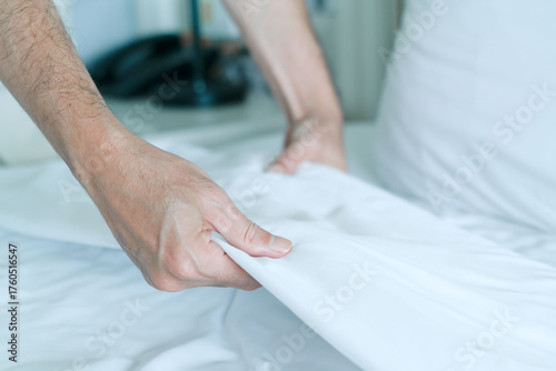 Hand set up white bed sheet in room hotel
