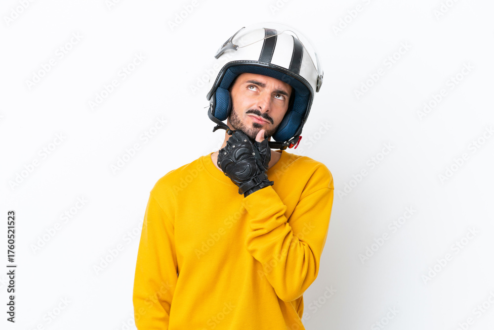 Fototapeta premium Young caucasian man with a motorcycle helmet isolated on white background having doubts