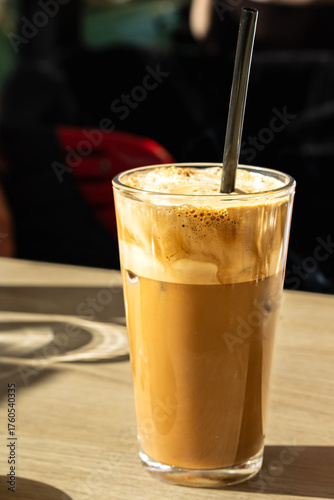 glass of greek iced frappe coffee with straw on wooden table