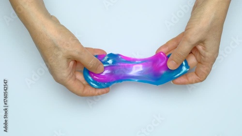 Human hands squeeze a viscous colorful slime. View from above. On a white background. Relaxation, calming down. 