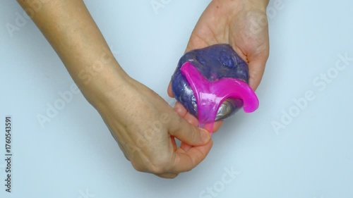 Human hands squeeze a viscous colorful slime. View from above. On a white background. Relaxation, calming down. 