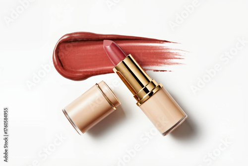 Top view of luxurious lipstick in a nude case with a gold stripe, next to a bright glossy stroke of deep burgundy on a white surface.