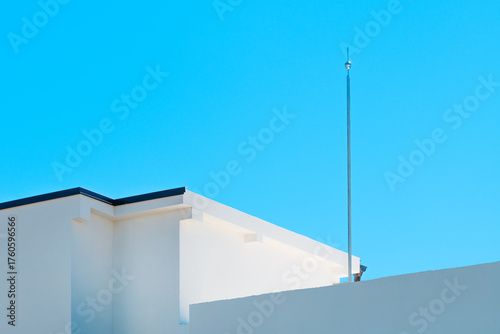 Bild auf Leinwand Lightning rod mounted on top of a building against clear blue sky, symbol of safety and protection