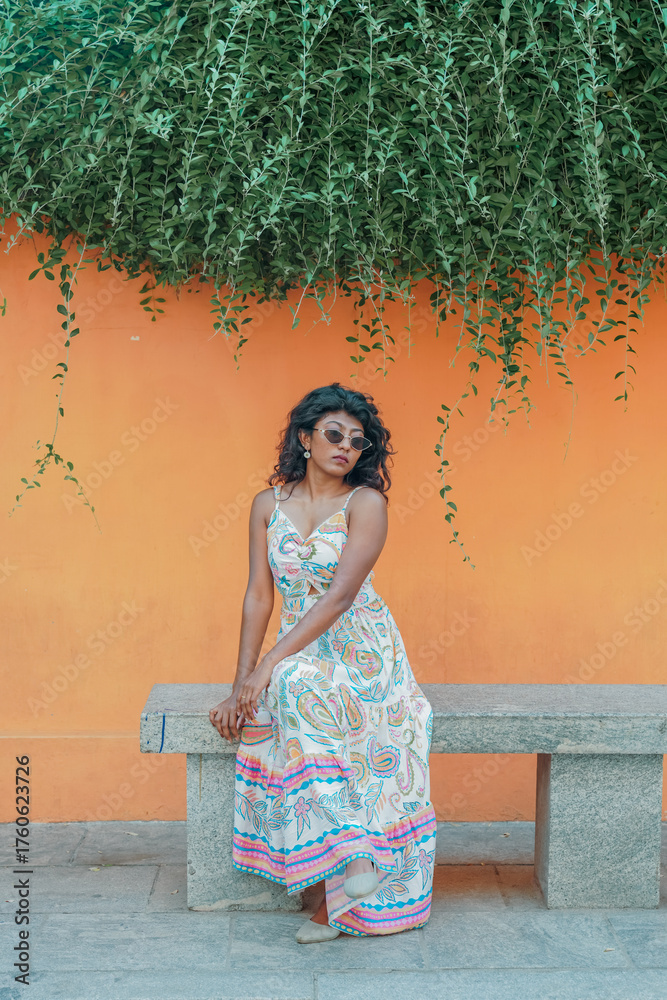 Fototapeta premium A woman is sitting on a bench wearing a white dress