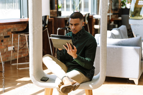 Foto A male worker looks at a computer tablet while sitting on a chair