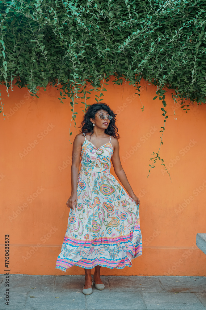 Fototapeta premium A woman in a white dress is standing in front of a green wall