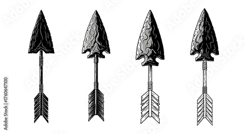 A collection of four ancient stone arrowheads with detailed fletching and shafts on a white background.