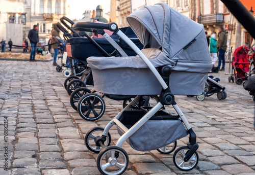 Row of empty stroll prams parked on city street paving stone