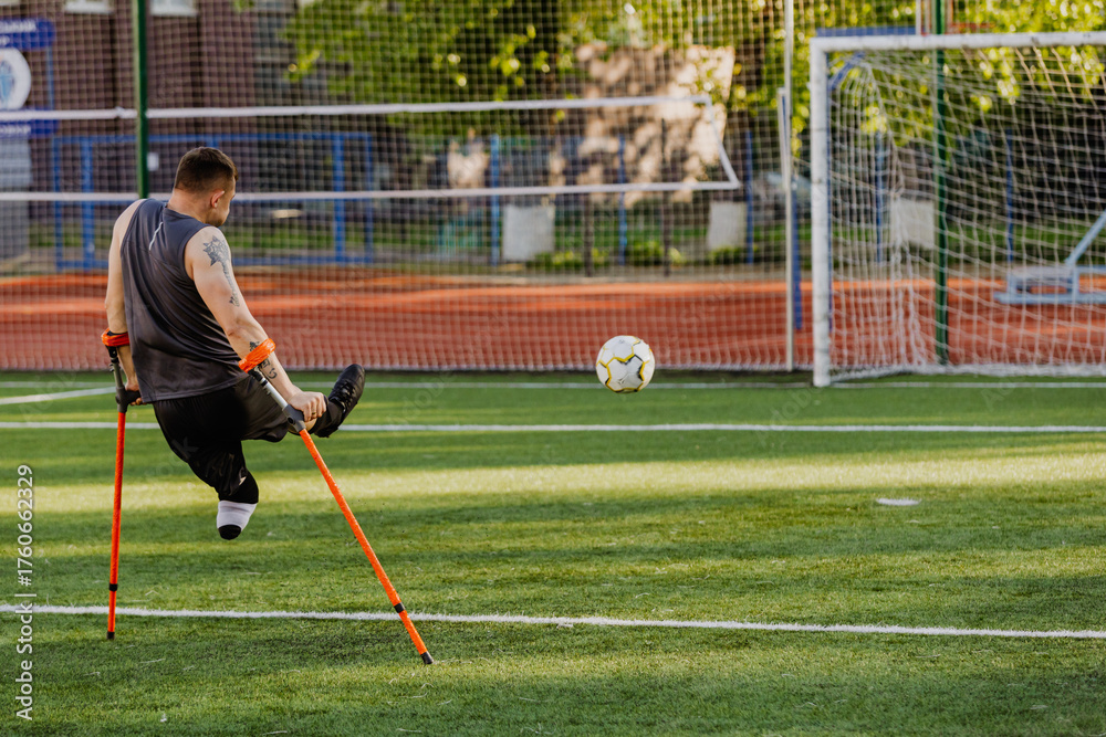 Obraz premium A man leans on crutches on the field after hitting the ball into the goal