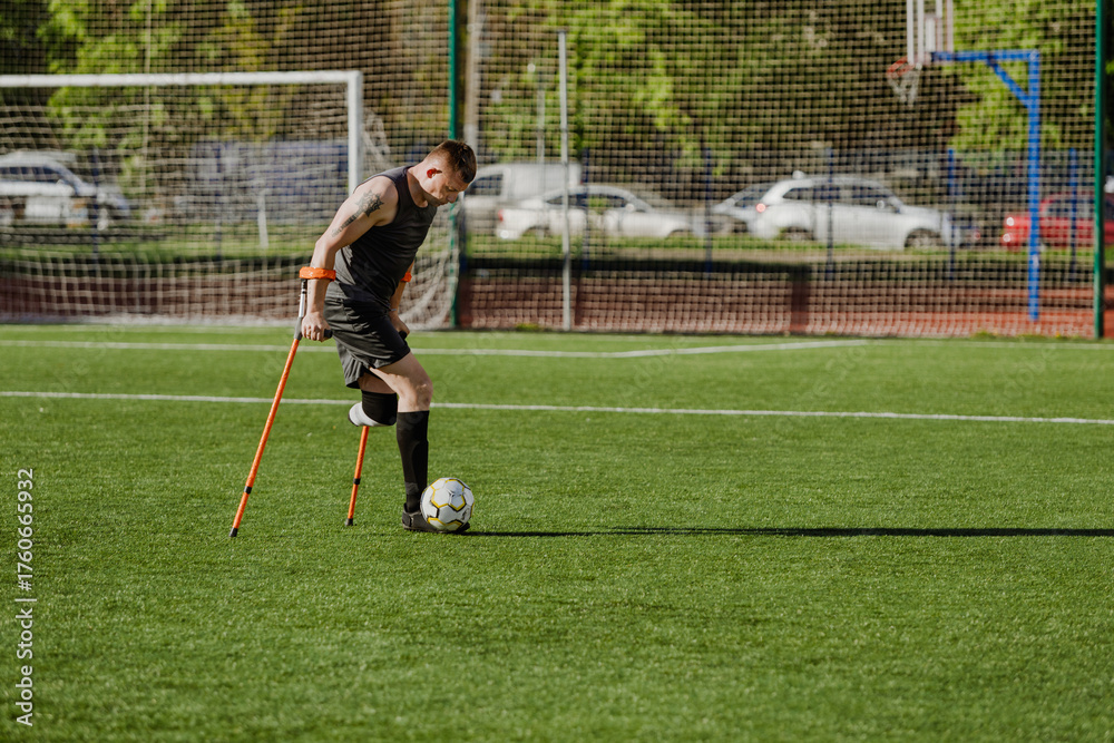 Obraz premium Man dribbles ball with foot and runs while holding crutches