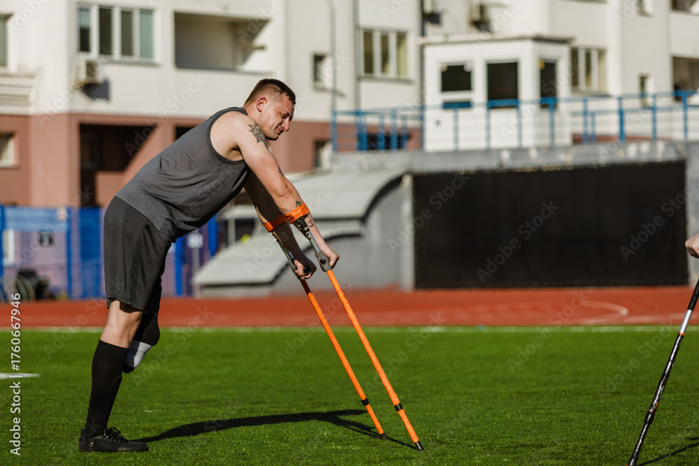 Obraz premium A male player stands bent over and rests his hands on crutches on the field
