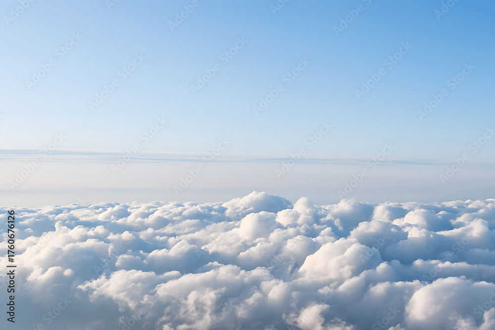 Naklejka premium Arial view from the airplane window shows a vast white cloudscape under a bright blue sky, resembling a heavenly landscape above the horizon