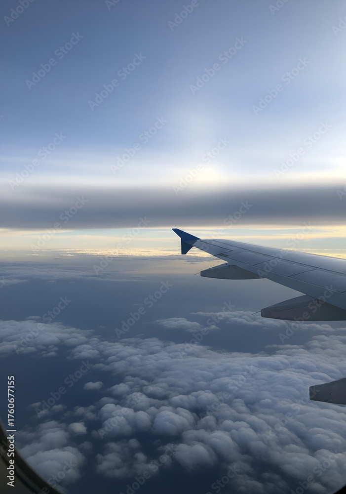 Obraz premium Vertical View from Airplane Window of Wing and Clouds at High Altitude