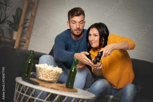 Happy couple play video games at home both are smiling,