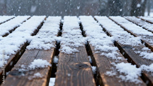 Snow falling on wooden planks of a deck in winter