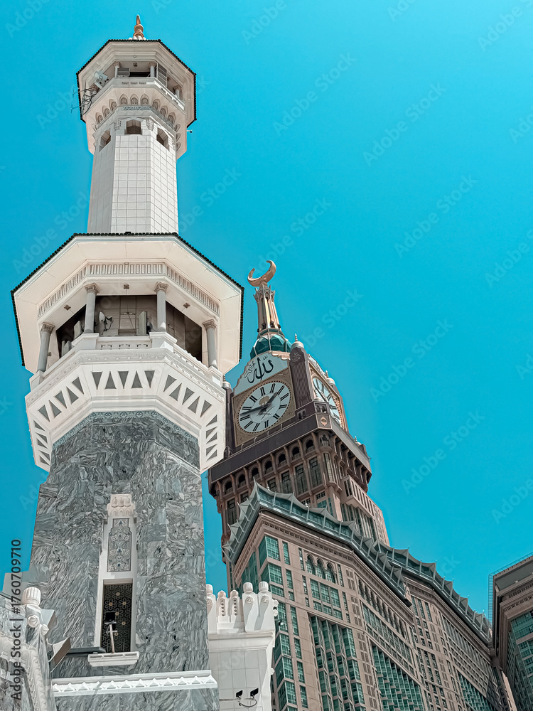 Fototapeta premium minaret of mosque, The majestic architecture of Mecca, Saudi Arabia. A minaret with intricate traditional Islamic design stands against a bright blue sky, with the modern Abraj Al Bait Clock Tower