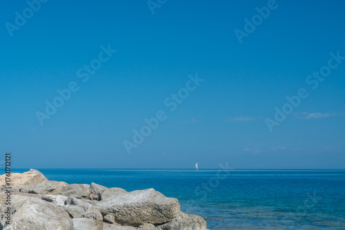 Single sailboat navigating Issyk-Kul Lakes waters. Sailing, recreational maritime sport. Yacht, Wind harnessing, sail trimming. Aquatic velocity pursuit, boating experience. Skilled sailors navigate