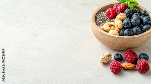 Fresh blueberries, raspberries, and mix of nuts including cashews and almonds are beautifully arranged in wooden bowl, creating healthy and vibrant snack option