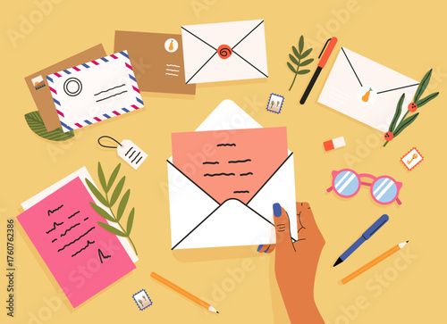 Hand opening envelope with letter, stationery flat lay for correspondence