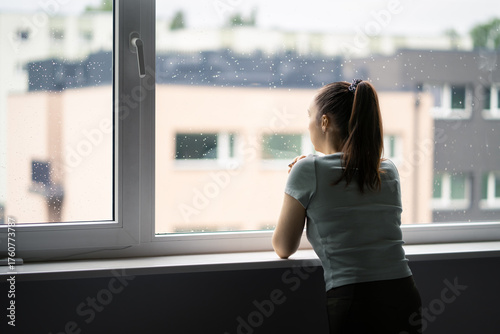 Patient in psychiatric hospital. Trauma and shame of victim of abuse. Depressed woman with schizophrenia or mental health disorder. Drug rehab treatment facility room. Rain and window.