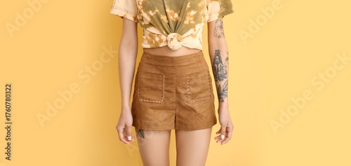 Tattooed young woman on yel...