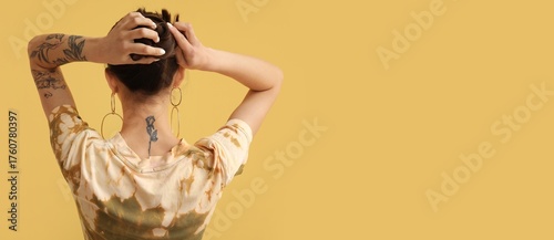 Tattooed young woman on yel...