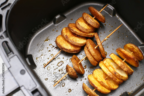 Wallpaper Mural Golden crispy fried potatoes on wooden skewers inside air fryer basket. Homemade snack preparation. Modern kitchen appliance concept. Healthy cooking alternative. Torontodigital.ca