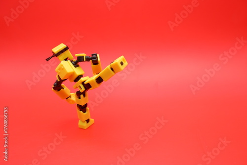 Yellow Dummy Action Figure Performing a Kick Pose on Red Background