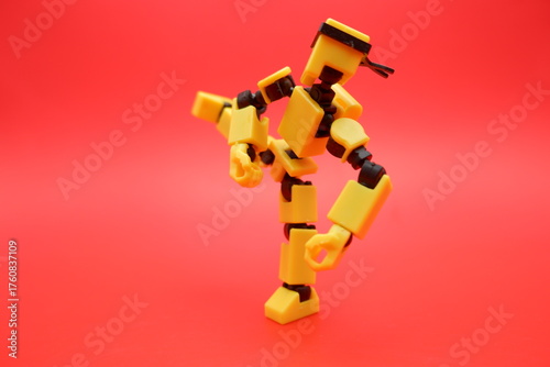 Yellow Dummy Action Figure Performing a Kick Pose on Red Background