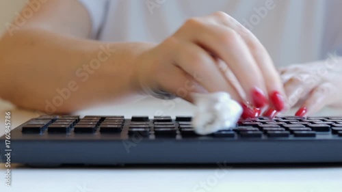 Black keyboard with a white background. A person is typing on the keyboard. The person is wearing a white shirt