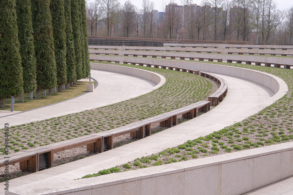 Obraz premium Walkway in Garden with curvy benches and tall trees