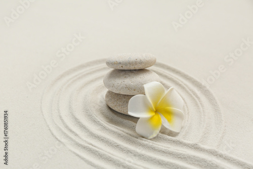 Canvas Print Spa stones and plumeria flower with lines on sand as background, closeup