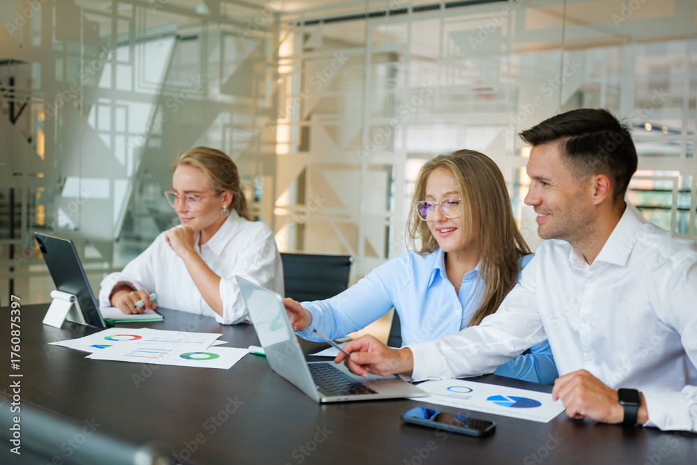 Fototapeta premium Team collaboration in a modern office setting with laptops and documents during a strategic planning session