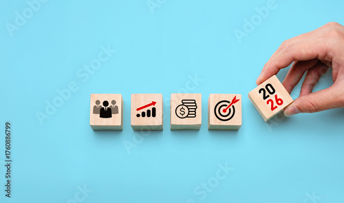 2026 business strategy planning concept with hand placing wooden blocks showing icons of team, growth, finance, and target, symbolizing future goals, leadership, development, and success planning