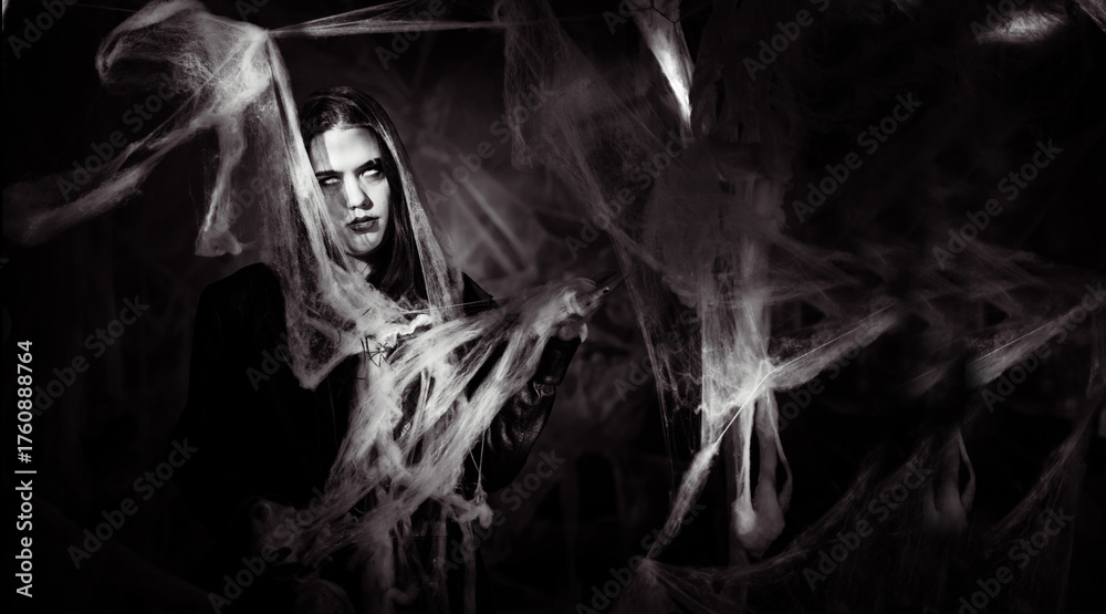 Naklejka premium gothic woman with creepy vampire makeup trapped in spider web. Fantasy scary girl on halloween background. Black and white photo