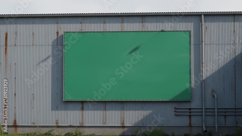 Large Green Screen Billboard Mounted on Corrugated Metal Wall for Advertising