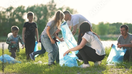Volunteers collect trash along river bank during community cleanup at park with group of family sorting waste near nature area to protect environment and keep river clean and safe supporting wildlife