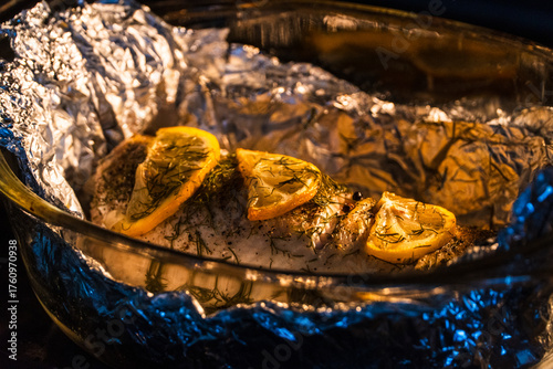 Fotografija Baked in the oven in foil with spices, herbs and lemon in a baking dish, top view