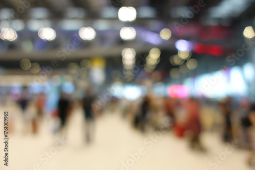 Blurred view of passengers and people at  International Airport. Travelers walking and checking flight information boards in the terminal. Busy atmosphere of people with luggage, lights, and airport.