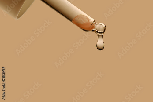 The texture of the serum flowing out of the pipette on a beige background.